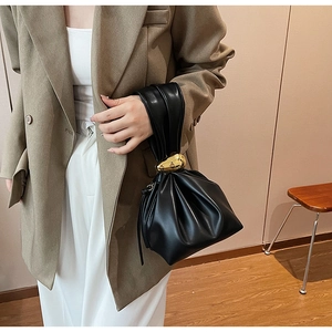 Detail of black pleated PU handbag featuring a unique gold-tone metal handle accessory