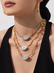 Detailed view of layered wavy necklace set with marquise cut zircon and gold hoop earrings