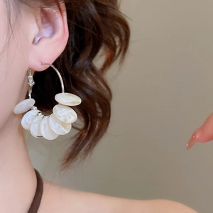 Detail of silver hoop earrings featuring white resin discs on a female model with brown hair