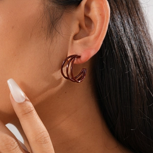 Detail view of dark brown triple-hoop C-shaped earrings on a model showing the chic design