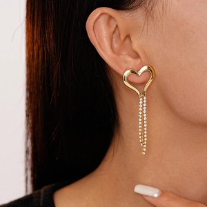 Detail view of heart tassel earrings with sparkling rhinestones on a female model