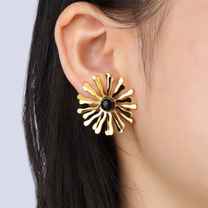 Boucles d'oreilles fleurs dorées vintage avec centre en émail noir portées par un mannequin