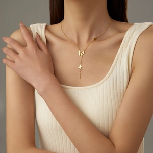 Detail of golden Y-shaped necklace with butterfly pendants on model collarbone