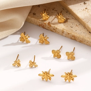 Brushed gold bee stud earrings for women with detailed wings on neutral stone display