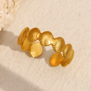 Détail d'une bague ajustable en forme de coquillage plaquée or 18 carats sur sable