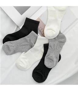 Cinque paia di calze in misto cotone in nero, bianco e grigio su sfondo di tessuto chiaro