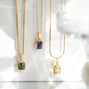 Dettaglio di collane placcate oro 18K con pietre preziose blu verdi e color champagne