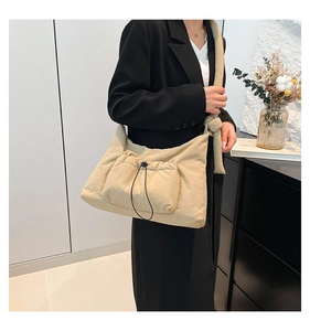 Detailed view of beige nylon crossbody bag featuring a front drawstring pocket design