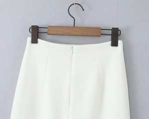 Detail of white high-waisted skirt featuring invisible zipper and woven texture