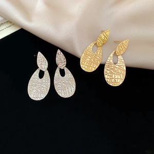 Detailed view of layered teardrop earrings with textured gold and silver metal finishes