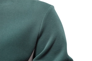 Close-up of the shoulder stitching and pique knit texture of a dark green sweatshirt
