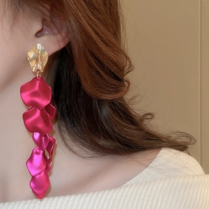 Close-up of long tassel earrings with golden leaf design and layered red petals