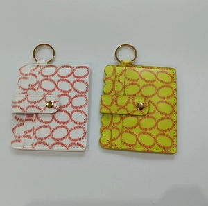 Detail of white and yellow baseball leather keychains with red stitching and gold rings