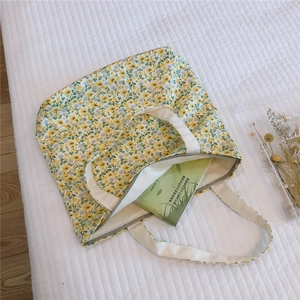 Detail of floral canvas tote bag with yellow flowers and zipper on white quilt