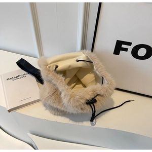 Detail of beige faux fox fur drawstring backpack with black straps on a white surface