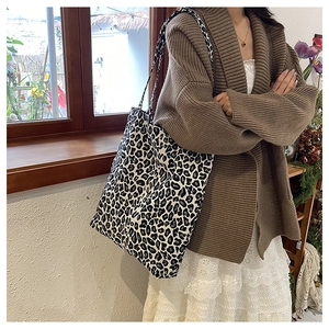 Detail of minimalist leopard print canvas tote bag carried by a model in a cafe