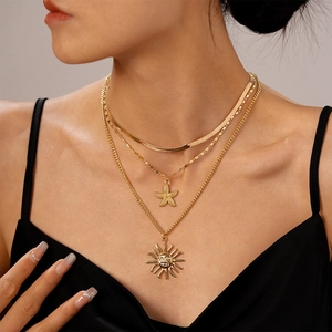 Close-up of layered gold necklace set featuring starfish and sun face pendants on skin