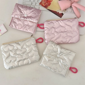Flat lay showing heart-quilted pouches in pink and silver with knot loops and zippers