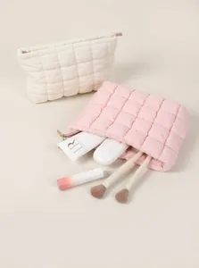 Gros plan de trousses à maquillage matelassées rose et blanc avec des accessoires