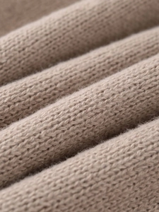 Macro shot of warm beige knit sweater showing soft texture and thick woven patterns