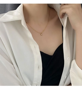 Close-up of a delicate gold titanium steel necklace with a purple pearl pendant on a model