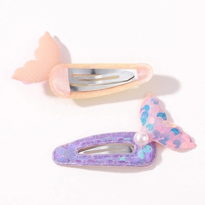 Close-up of glitter mermaid tail hair clips with pearls and fabric texture details