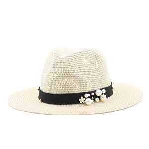 Detail of light beige straw hat with black pearl ribbon and small white flower