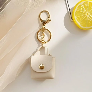 Macro detail of the beige PU leather mini bag keychain with gold lobster clasp and ring