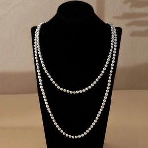 Close-up of layered silver long pearl necklace on a black velvet mannequin stand