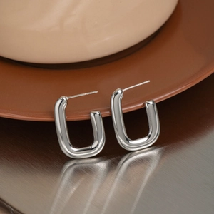 Close-up of silver U-shaped earrings with S925 hallmark on minimalist polished metal