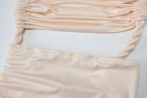 Close-up of ruched beige fabric and twisted cord shoulder strap on summer dress