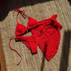 Macro detail of red textured bikini three-piece set showing seersucker fabric on a straw mat