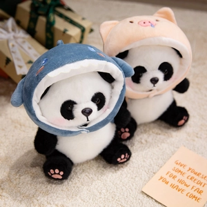 Panda plush toy in shark and pig hoodies on a cozy rug with gift box