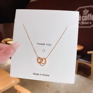 Close-up of interlocking heart necklace in rose gold displayed on a white product card