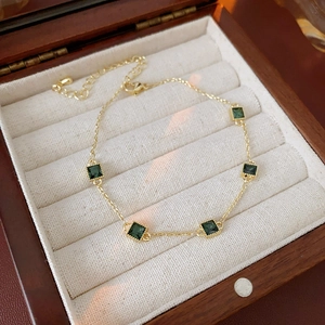 Détail du bracelet plaqué or avec cinq zircons verts carrés sur doublure en velours