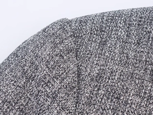 Close-up of shoulder stitching on a grey herringbone tweed blazer with pleated sleeves