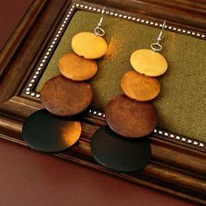 Macro detail of Bohemian round wood disc earrings with gradient brown tiers and silver hooks