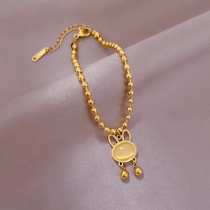 Detail of golden bunny bracelet with cat eye stone pendant on soft velvet background