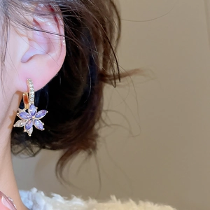 Detail view of elegant flower drop earrings with purple crystals on a female model