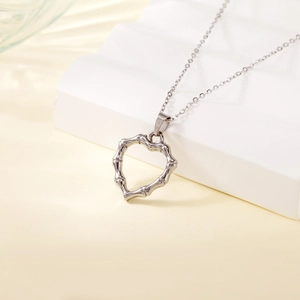 Silver heart pendant necklace with bamboo texture on white geometric steps