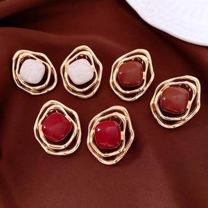 Detailed view of hollow irregular diamond earrings in cream and burgundy enamel