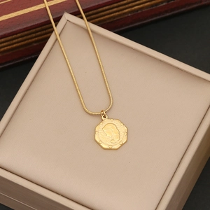 Close-up of gold rose pendant on a snake chain displayed over a beige jewelry box