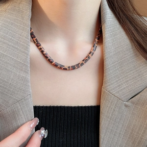 Nahaufnahme der flachen Schlangenkette mit Leopardenmuster an Model in beigem Blazer