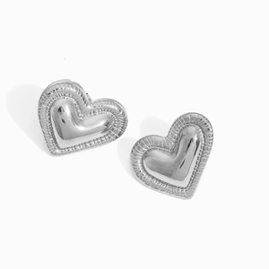 Macro view of silver heart stud earrings featuring detailed radial pleated edge textures