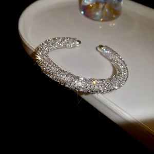 Close-up of a silver-colored open cuff bracelet with pavé-set shimmering crystals