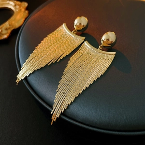 Detailed macro view of golden chain tassel earrings on a premium black display tray
