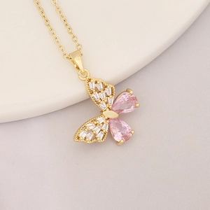Detail of a gold butterfly necklace featuring pink pear-shaped and clear baguette stones