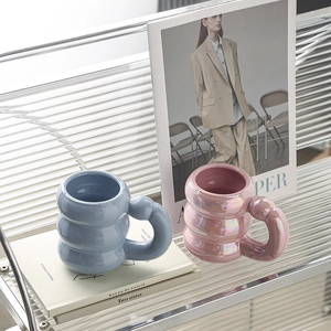 Close-up of blue and pink ceramic mugs featuring a unique cloud-shaped handle design