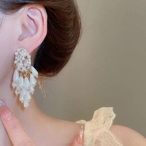Detail of elegant teardrop pearl tassel earring with crystal accents on female model