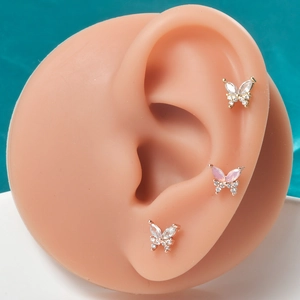 Detailed view of zircon butterfly cartilage studs on ear model with silk background